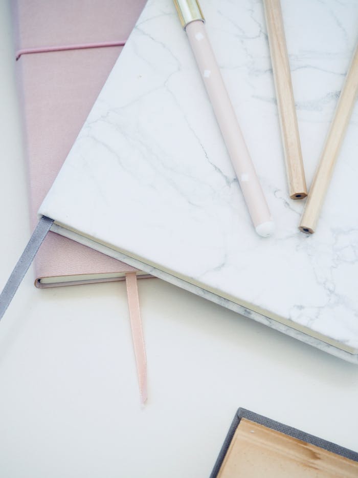 About Stylish marble and pink notebooks paired with pens, creating an elegant and clean office desk setup.
