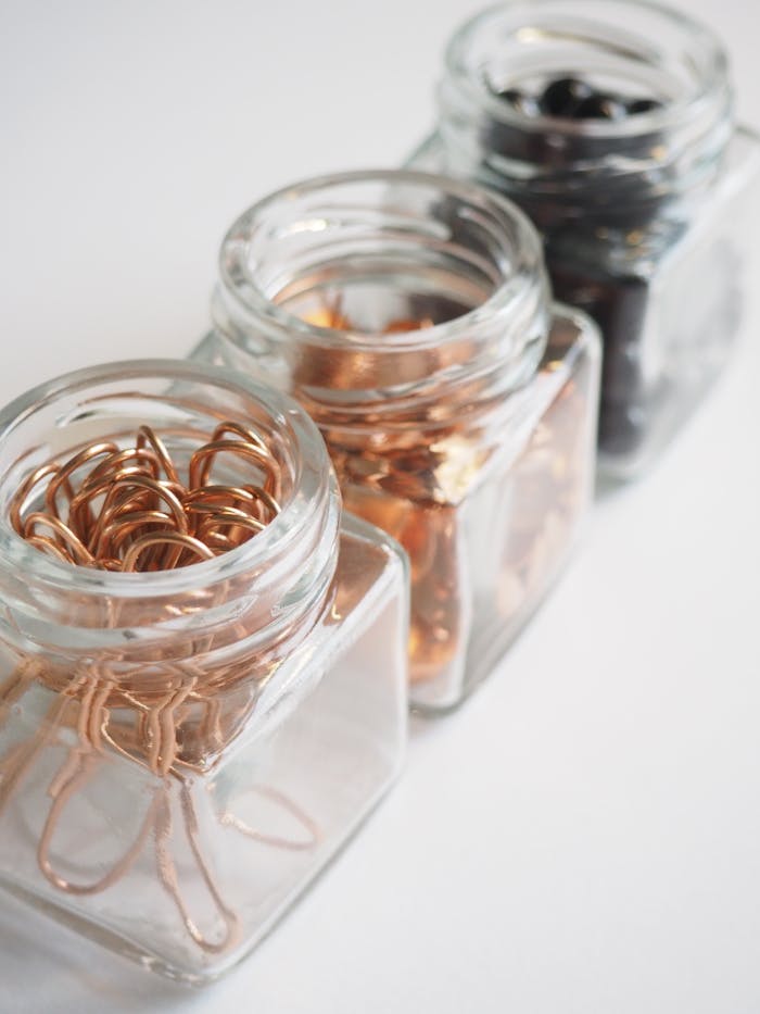 Home Close-up of paperclips and pins in glass jars, ideal for office decor inspiration.